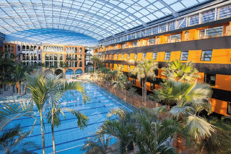 Palmen, Wellenlagune, warmes Wasser – Besucher der Therme Erding können sich mit einer Mischung aus Spaß und Entspannung fallen lassen. Unter riesigen Glaskuppeln und im Freien warten die unterschiedlichsten Becken, Europas größte Rutschenwelt sowie 26 Themen-Saunen auf alle Wasserratten.